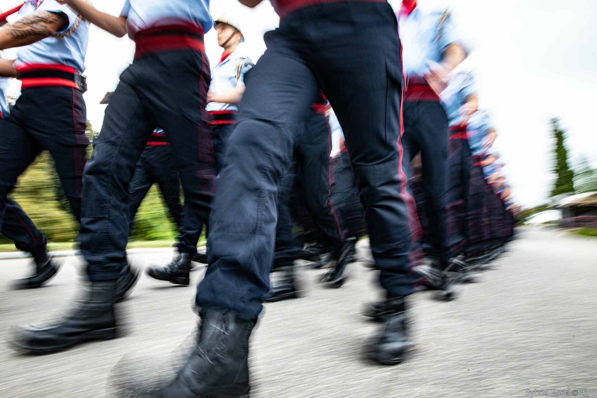jambes en mouvement de pompiers de Paris marchant au pas en tenue chemisette bleue et pantalon F1.