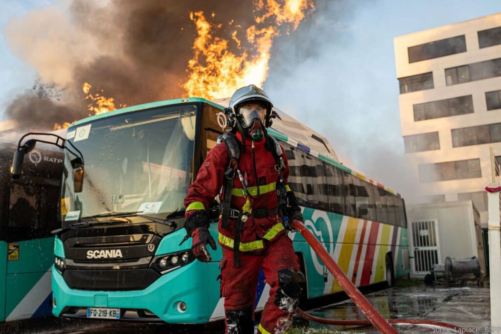 Bus en feu lors d'un incendie à Aubervilliers en décembre 2023, avec un sapeur-pompier de Paris devant.