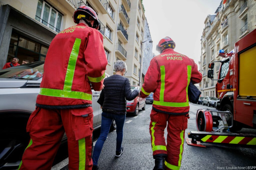 Sapeurs-pompiers de Paris sur intervention pour un feu d'appartement à Paris 16e arrondissement en train d'accompagner une victime