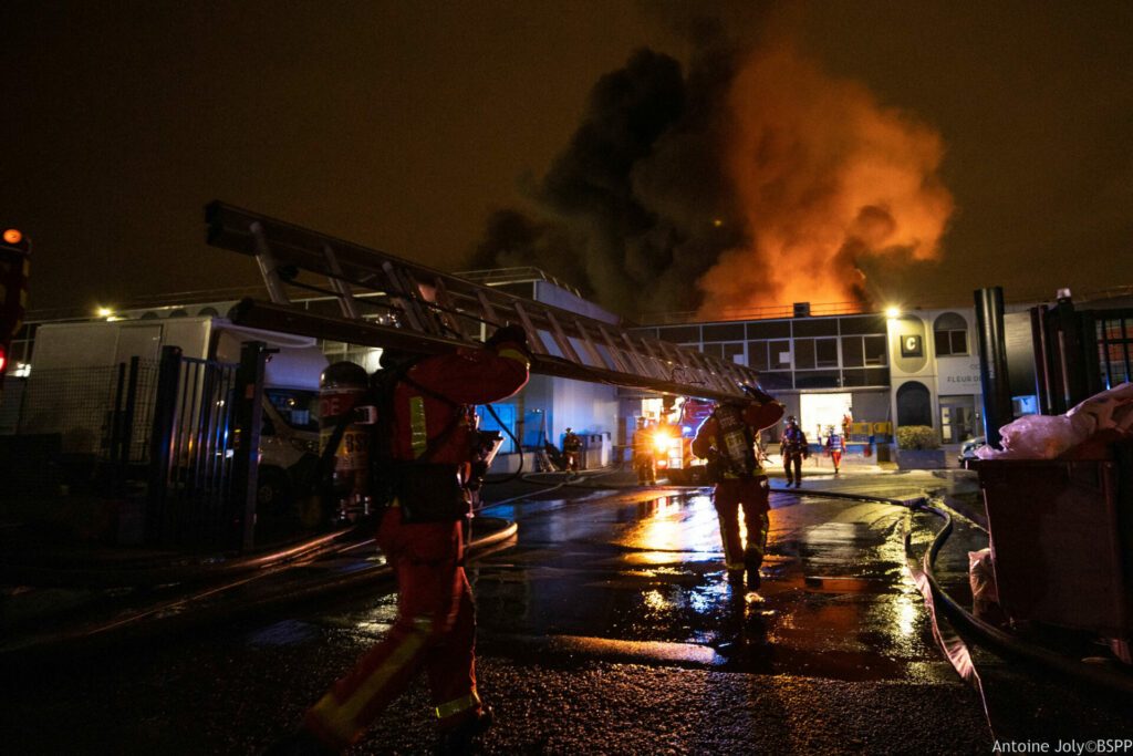 Sapeurs-pompiers de Paris de la BSPP intervenant sur un feu d'entrepôt à Saint-Denis (93) le 1er février 2024, portant une échelle