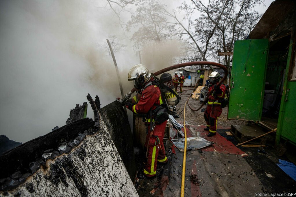 Sapeurs-pompiers de Paris en intervention sur un feu d'installations précaires à Antony, en train de parfaire l'extinction du feu.