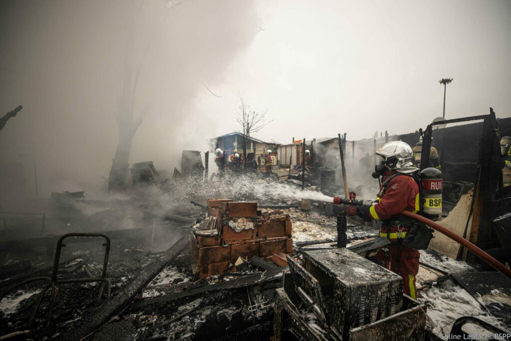 Sapeurs-pompiers de Paris en intervention sur un feu d'installations précaires à Antony,  en train d'éteindre le sinistre avec une lance.