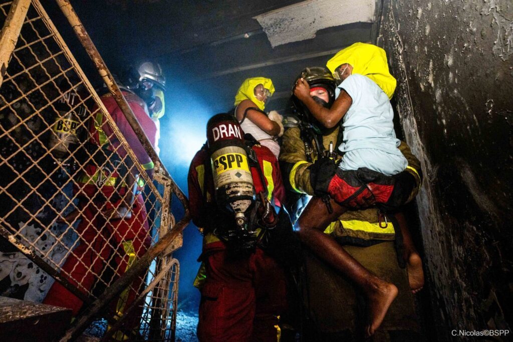 Pompiers effectuant le sauvetage d'un enfant lors d'un feu d'immeuble